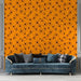 Un salon moderne avec un papier peint orange vif orné de motifs floraux noirs, créant une ambiance chaleureuse et dynamique.