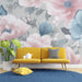 Un salon lumineux avec un papier peint floral aux grandes fleurs roses et bleues sur fond gris, créant une atmosphère douce et apaisante.
