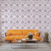 Un salon contemporain avec un papier peint floral violet sur fond clair, créant une atmosphère douce et élégante, agrémenté d'un canapé orange vibrant.