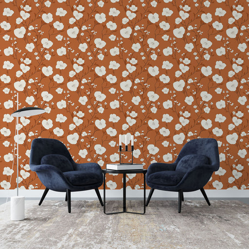 Un salon contemporain avec un papier peint floral sur fond terracotta, orné de grandes fleurs blanches et de délicates branches, créant une atmosphère chaleureuse et accueillante.