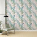Une pièce lumineuse avec un papier peint floral aux motifs de fougères dans des teintes douces de vert, bleu et rose, créant une atmosphère apaisante et naturelle.