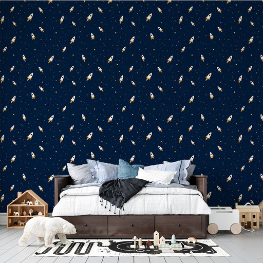 Une chambre d'enfant avec un papier peint bleu nuit orné de fusées blanches et dorées, créant une atmosphère ludique et imaginative.