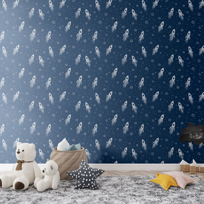 Une chambre d'enfant avec un papier peint bleu nuit orné de fusées blanches et de bulles, créant une atmosphère ludique et imaginative.