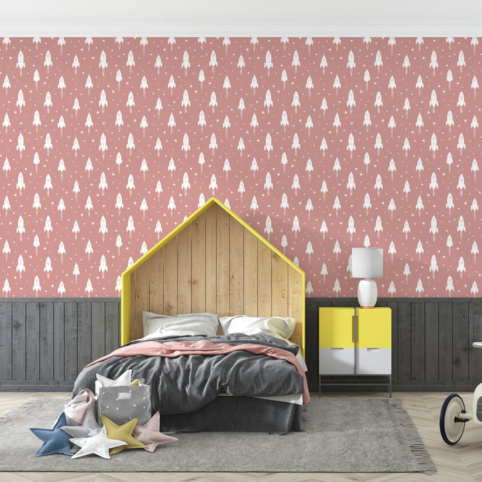 Une chambre d'enfant avec un papier peint rose aux motifs de fusées blanches, créant une ambiance ludique et imaginative.
