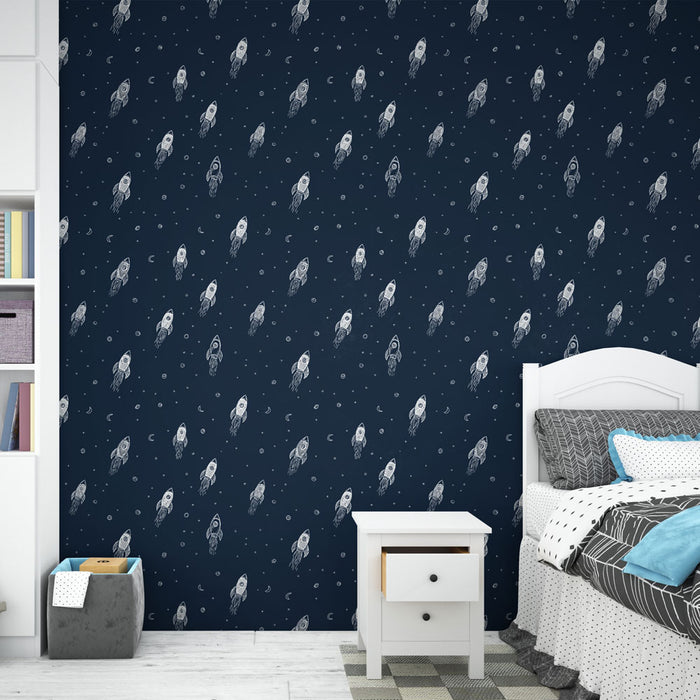 Une chambre enfantine avec un papier peint bleu marine orné de fusées blanches et de motifs célestes, créant une ambiance ludique et rêveuse.