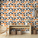 Une entrée moderne avec un papier peint graphique aux motifs géométriques noirs et orange sur fond crème, créant une atmosphère dynamique et chaleureuse.