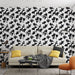 Un salon moderne avec un papier peint noir et blanc aux motifs de feuilles de ginkgo, créant une atmosphère élégante et artistique.