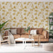 Un salon accueillant avec un papier peint floral aux motifs de feuilles de ginkgo dans des teintes dorées sur fond crème, créant une atmosphère douce et naturelle.