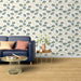 Un salon moderne avec un papier peint aux motifs de feuilles de ginkgo dans des teintes vertes et beiges, créant une atmosphère naturelle et apaisante.