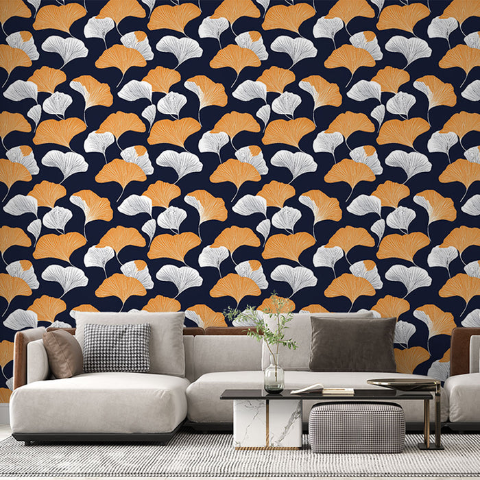 Un salon moderne avec un papier peint aux motifs de feuilles de ginkgo orange et blanches sur fond bleu nuit, créant une atmosphère chaleureuse et élégante.