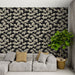 Un salon contemporain avec un papier peint noir orné de motifs de feuilles de ginkgo en beige, créant une ambiance élégante et apaisante.