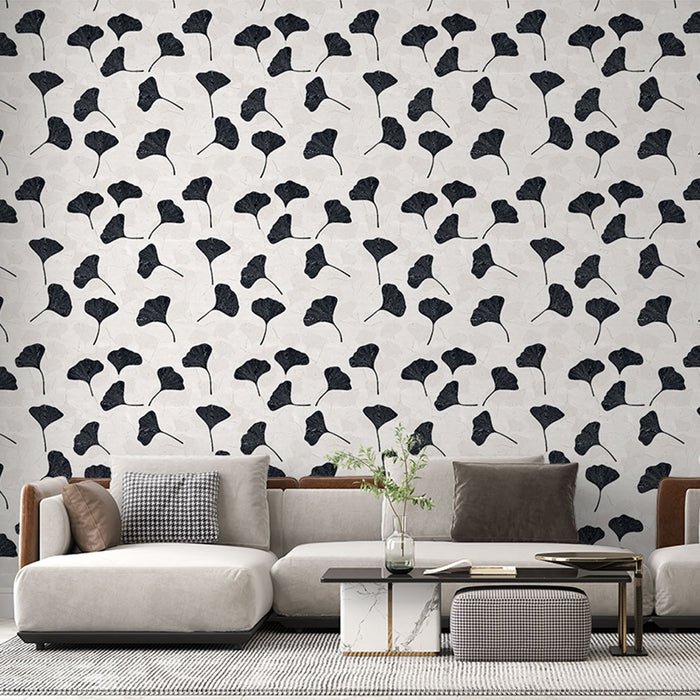 Un salon moderne avec un papier peint aux motifs de feuilles de ginkgo en noir sur fond clair, créant une ambiance élégante et artistique.