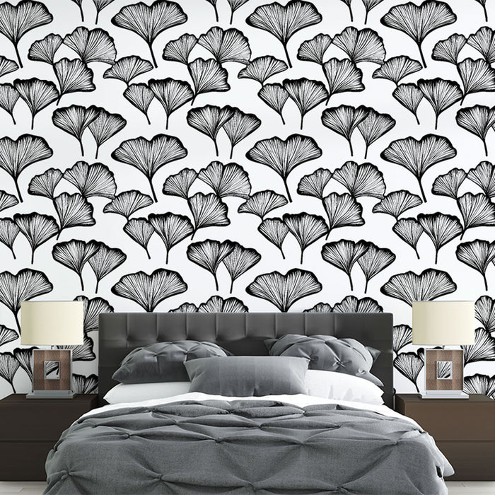 Une chambre moderne avec un papier peint floral noir et blanc représentant des feuilles de ginkgo, créant une ambiance élégante et artistique.