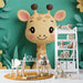 Une chambre d'enfant avec un papier peint représentant une girafe souriante sur fond vert, créant une ambiance joyeuse et ludique.