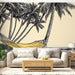 Un salon lumineux avec un papier peint illustrant des palmiers et un hamac sur fond beige, créant une atmosphère relaxante et tropicale.