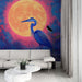 Un salon moderne avec un papier peint artistique représentant un héron bleu majestueux devant une pleine lune orange sur fond coloré, créant une atmosphère vibrante et poétique.