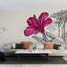 Un salon moderne avec un papier peint artistique représentant une grande fleur rose stylisée et une main sur fond neutre, créant une ambiance chaleureuse et inspirante.