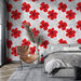 Une chambre moderne avec un papier peint floral aux grandes fleurs rouges sur fond blanc, créant une ambiance tropicale et vivifiante.