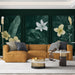 Un salon élégant avec un papier peint vert foncé illustrant de grandes feuilles et des fleurs blanches et jaunes, créant une ambiance tropicale et apaisante.