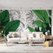Un salon moderne avec un papier peint tropical aux grandes feuilles vertes sur fond blanc, créant une ambiance fraîche et vivifiante.