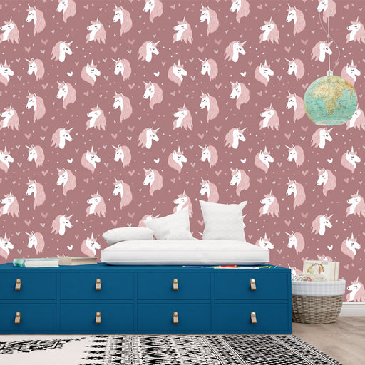 Une chambre enfantine avec un papier peint rose illustré de licornes blanches et roses, créant une atmosphère ludique et féerique.