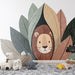 Une chambre d'enfant avec un papier peint illustrant un lion souriant entouré de grandes feuilles colorées, créant une atmosphère ludique et chaleureuse.
