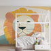 Une chambre d'enfant avec un papier peint illustrant un lion stylisé aux couleurs douces et chaudes, créant une atmosphère ludique et accueillante.