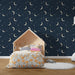 Une chambre enfantine avec un papier peint bleu nuit orné de croissants de lune et d'étoiles scintillantes, créant une ambiance rêveuse et apaisante.