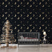 Une chambre moderne avec un papier peint noir étoilé orné de croissants de lune dorés, créant une atmosphère rêveuse et apaisante.