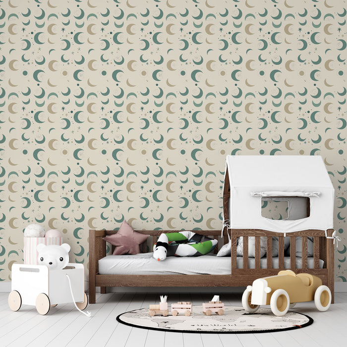 Une chambre d'enfant avec un papier peint aux motifs de lunes et d'étoiles dans des teintes douces de vert et beige, créant une atmosphère rêveuse et apaisante.