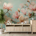 Une pièce lumineuse avec un papier peint floral représentant de grandes fleurs de magnolia aux teintes douces sur fond turquoise, créant une atmosphère apaisante et élégante.