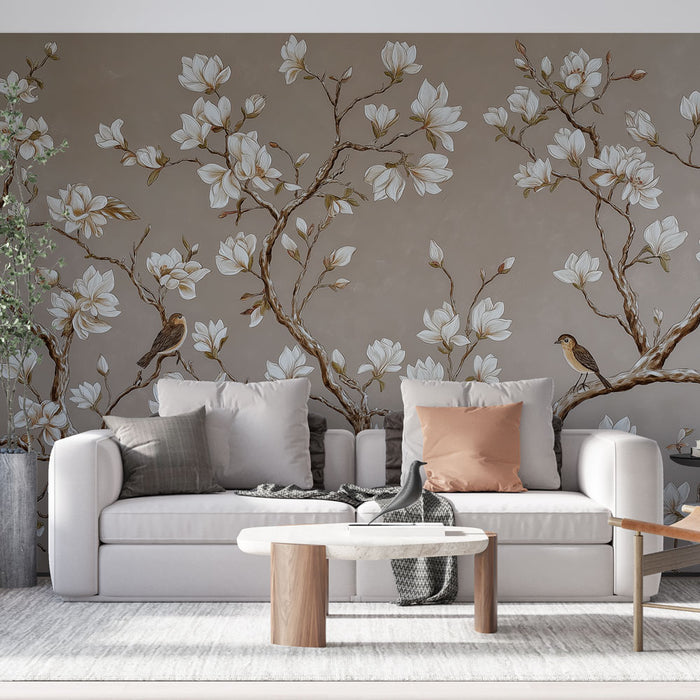 Un salon élégant avec un papier peint floral représentant des magnolias blancs et des oiseaux sur un fond taupe, créant une atmosphère douce et apaisante.