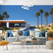 Une pièce moderne avec un papier peint représentant une villa contemporaine sous un ciel bleu, entourée de palmiers et de dunes, créant une ambiance estivale et relaxante.