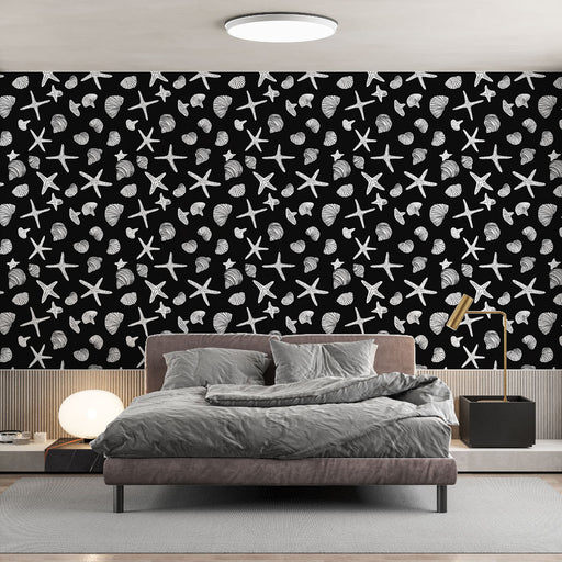 Une chambre contemporaine avec un papier peint noir orné de motifs de coquillages et d'étoiles de mer en blanc, créant une ambiance marine et ludique.