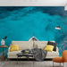 Un salon moderne avec un papier peint représentant une vue aérienne de la mer turquoise, évoquant une atmosphère apaisante et estivale.