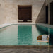Une pièce moderne avec un papier peint représentant une piscine turquoise entourée de murs en pierre, évoquant une ambiance zen et relaxante.
