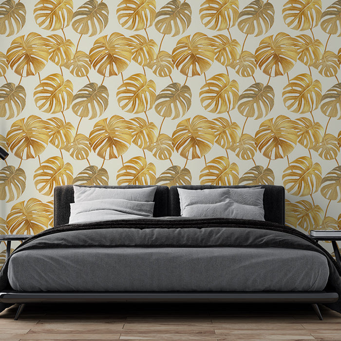Une chambre moderne avec un papier peint tropical aux motifs de grandes feuilles de monstera dorées sur fond clair, créant une atmosphère chaleureuse et accueillante.