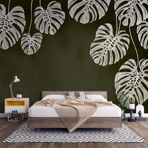 Une chambre moderne avec un papier peint vert foncé orné de grandes feuilles de monstera blanches, créant une atmosphère tropicale et apaisante.