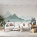 Un salon lumineux avec un papier peint représentant des montagnes en dégradés de vert et des arbres sombres, créant une ambiance apaisante et naturelle.