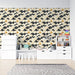 Une chambre d'enfant avec un papier peint aux motifs de montagnes stylisées en noir et or sur fond crème, créant une atmosphère ludique et moderne.