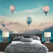 Une chambre moderne avec un papier peint représentant des montgolfières colorées sur fond de montagnes pastel, créant une atmosphère rêveuse et apaisante.