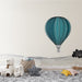 Une chambre d'enfant avec un papier peint illustrant une montgolfière turquoise stylisée sur un fond clair, créant une ambiance ludique et rêveuse.