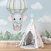 Une chambre d'enfant avec un papier peint illustrant un éléphant mignon dans un ballon dirigeable sur fond bleu clair, créant une atmosphère douce et ludique.
