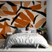Une chambre moderne avec un papier peint abstrait aux motifs organiques dans des teintes terracotta et noir, créant une atmosphère chaleureuse et contemporaine.
