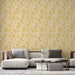 Un salon moderne avec un papier peint aux motifs de feuilles jaunes et beige sur fond clair, créant une ambiance chaleureuse et accueillante.