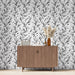 Une salle à manger moderne avec un papier peint noir et blanc aux motifs de feuilles délicates, créant une ambiance élégante et apaisante.