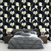Une chambre moderne avec un papier peint floral aux motifs de feuilles blanches et dorées sur fond noir, créant une ambiance élégante et sophistiquée.