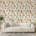 Un salon moderne avec un papier peint floral aux motifs de feuilles stylisées en orange, gris et beige sur fond clair, créant une ambiance chaleureuse et accueillante.
