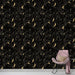 Un salon élégant avec un papier peint noir orné de motifs floraux dorés, créant une ambiance sophistiquée et chaleureuse.