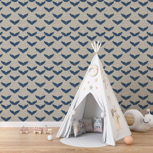 Une chambre d'enfant avec un papier peint représentant des motifs de nageoires de baleine en bleu sur fond beige, créant une atmosphère douce et ludique.